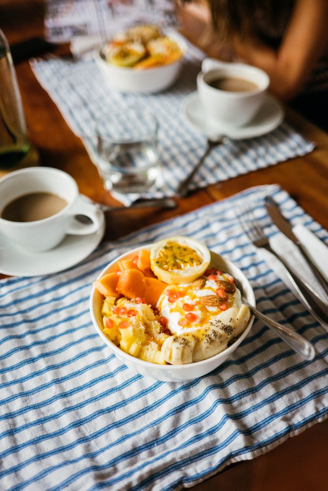 Table set with bowl of fresh fruit breakfast with nuts, honey and yogurt, vertical