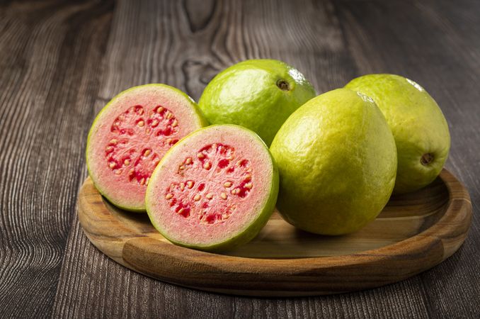 Fresh sliced guavas on wooden table.