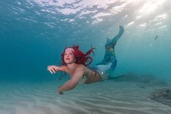 Redhead fairytale female mermaid swimming underwater