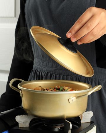 Cook opening brass pot while cooking noodles