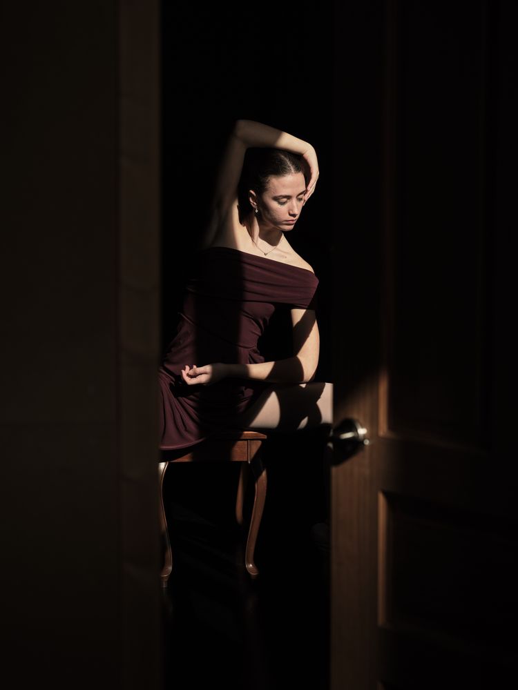 Sensual ballerina sitting on chair and touching head