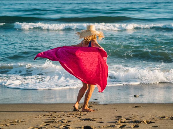 Woman with pink pareo on sandy beach
