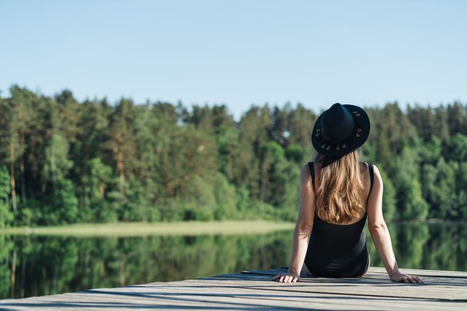 Young female sitting on pier on nature