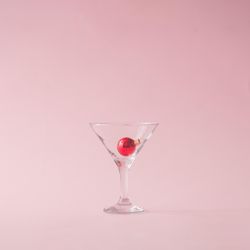Christmas tree decoration in martini glass on pastel pink background with creative copy space