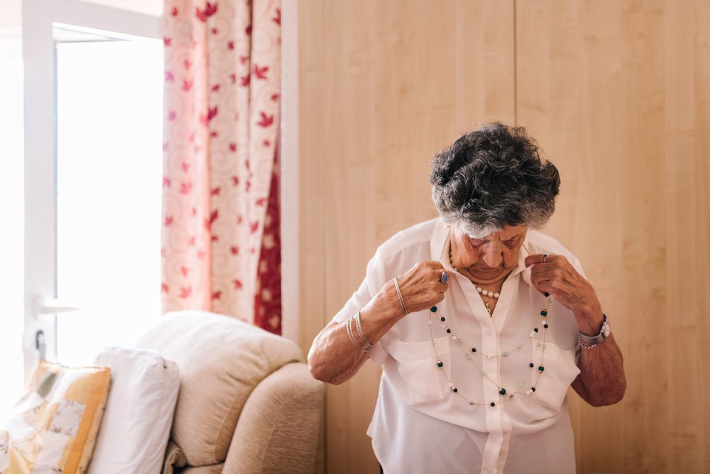 Mature woman standing near armchair at home