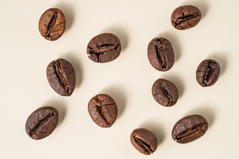 Flat lay of roasted coffee beans scattered on a surface.