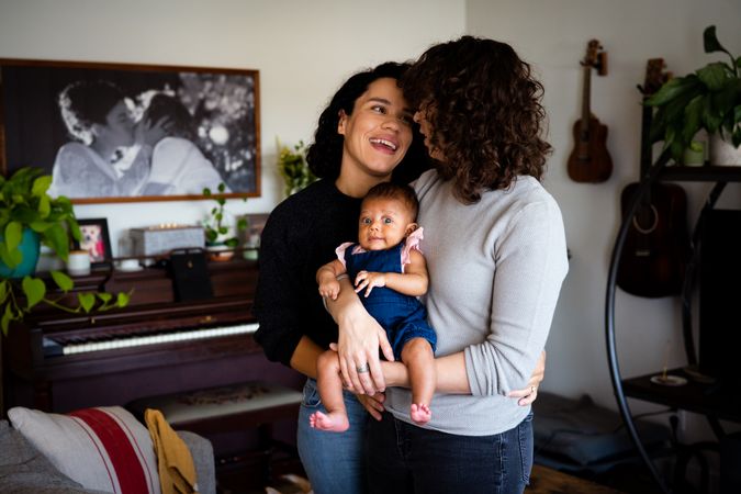 Two woman looking at each other while holding their newborn baby