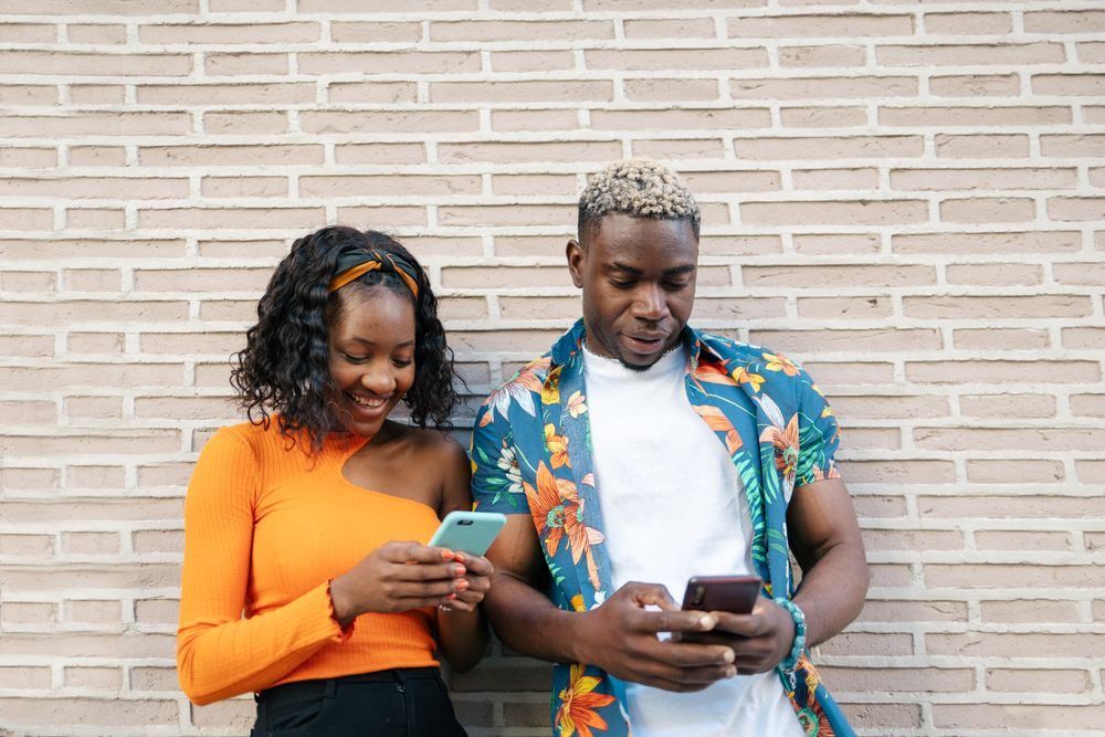 Young Black friends using smartphone in the street