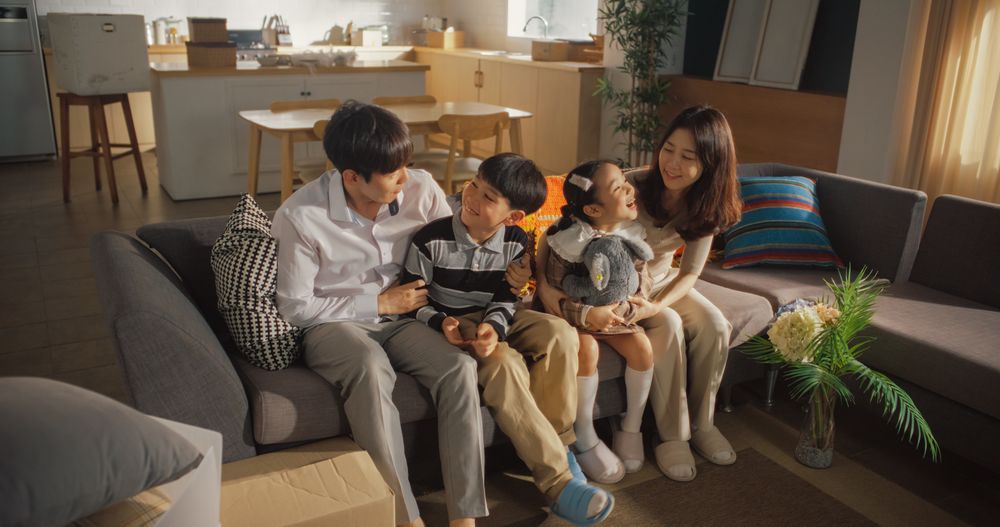 Family Moving in: Happy Young Korean Couple and Their Kids Sitting in Their Newly Purchased Apartment.