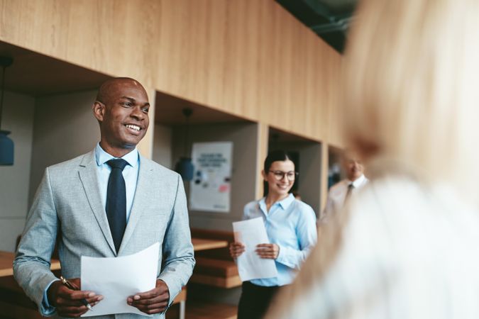 Group of people standing in open office with noted