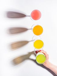 Hand and glasses of bright colorful drinks on table