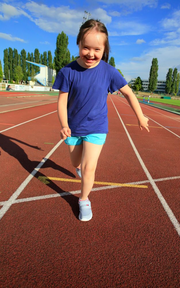 Young child running across finish line on running track
