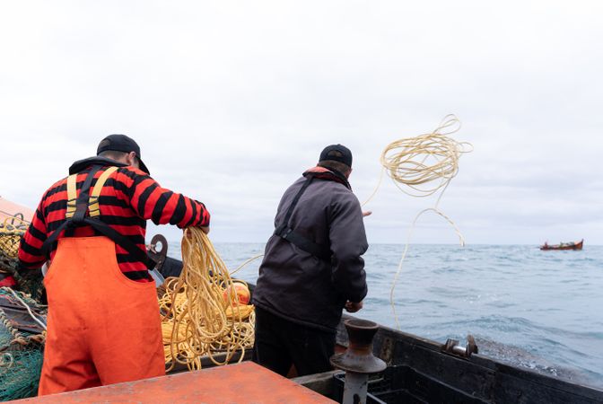 Two fishermen throwing nets to catch lobsters in the sea