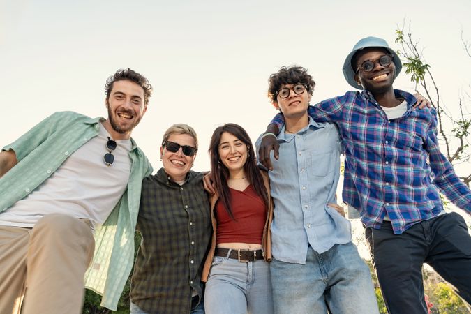 Low angle portrait of a happy diverse group of friends smiling at camera.