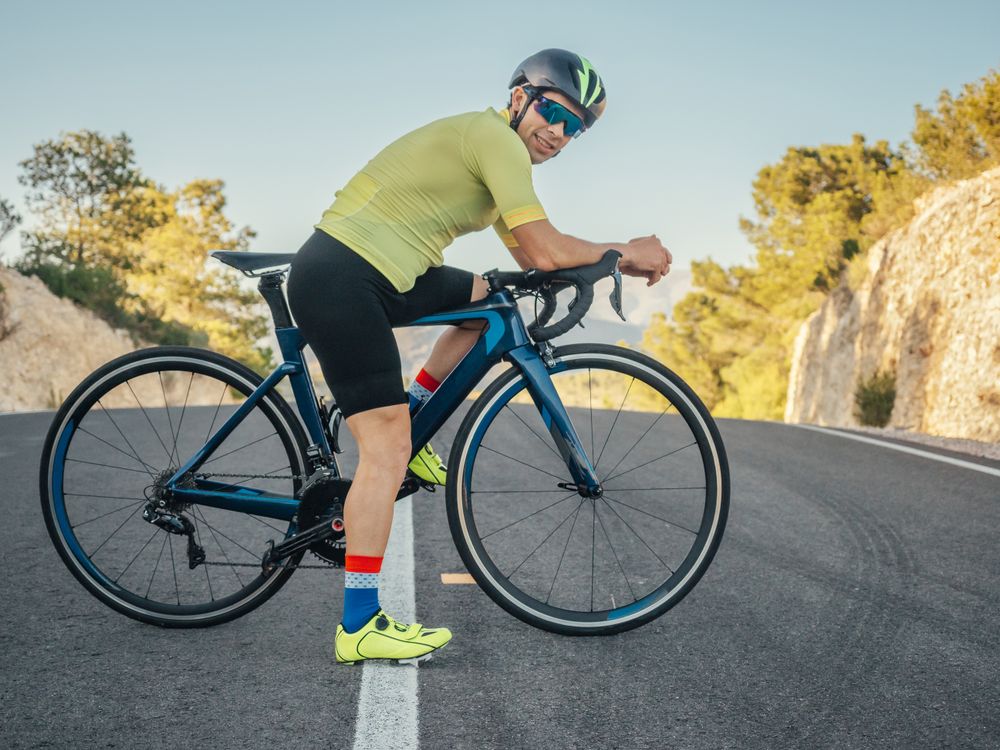 man resting and enjoying the views while riding a bicycle on a mountain road