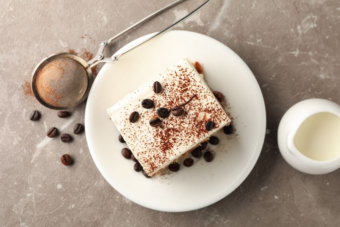 Composition with plate of tiramisu on light brown background. Tasty dessert