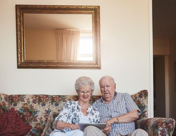 Mature man and woman using touchscreen computer at nursing home