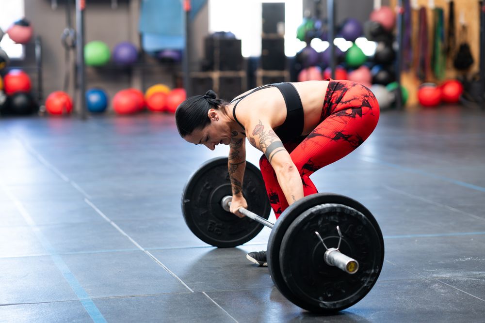 Side view of woman deadlifting bar bell