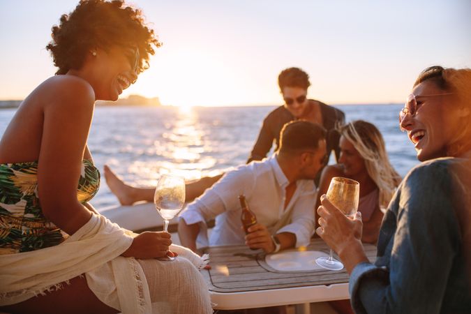 Group of men and women having fun at boat party during sunset