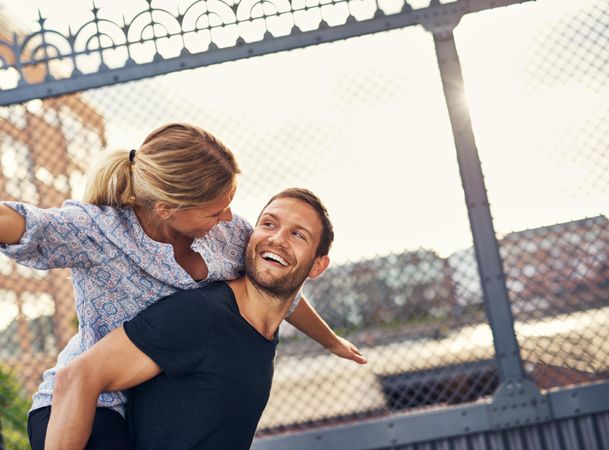 Woman on man’s back with her arms outstretched