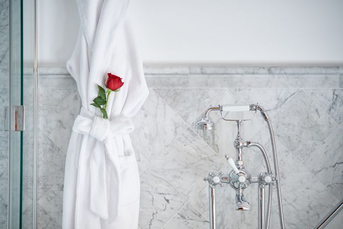 Interior of luxury bathroom with terry bathrobe with red rose