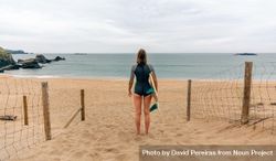 Woman standing on beach with surfboard enjoying beautiful view bDkpE4