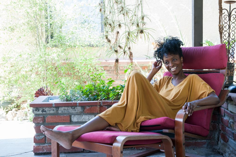 Full length side portrait of woman sitting in pink chair