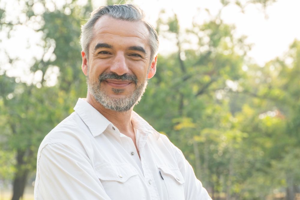 Content grey haired man standing in a park