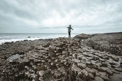 Female standing on cliff and contemplating