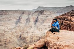 Male having rest on edge of rock and relishing beverage