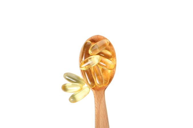 Wooden spoon with omega pills, isolated on blank background
