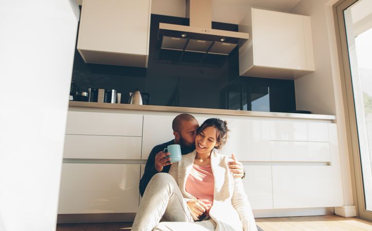 Romantic young couple sitting on floor in kitchen