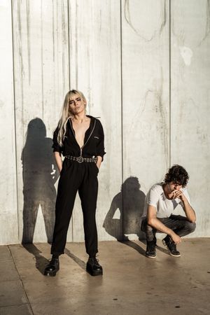 Rebellious trendy confident woman and calm guy against gray wall