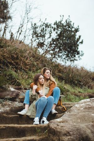 Young sisters sitting on stone stairs on spring day