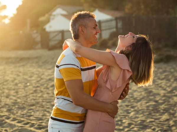 Laughing couple hugging on sandy beach