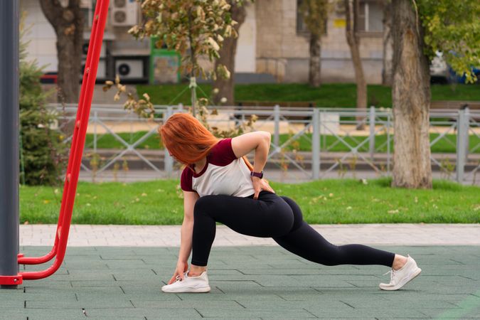 Woman in deep lunge stretch, hand touching foot