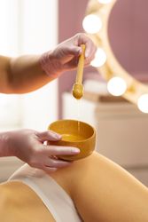 Therapist preparing honey mixture during beauty body treatment.
