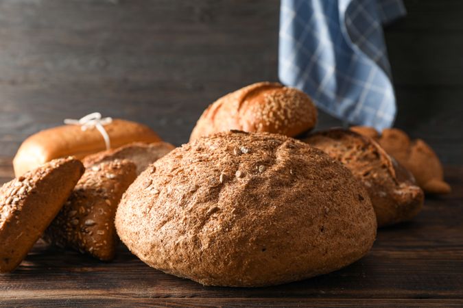 Bakery products and kitchen towel on wooden table against wood background, space for text and closeup