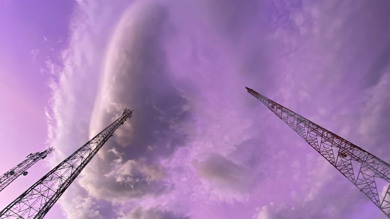 telecommunication towers reach towards the sky, contrasting against the purple hues of the clouds
