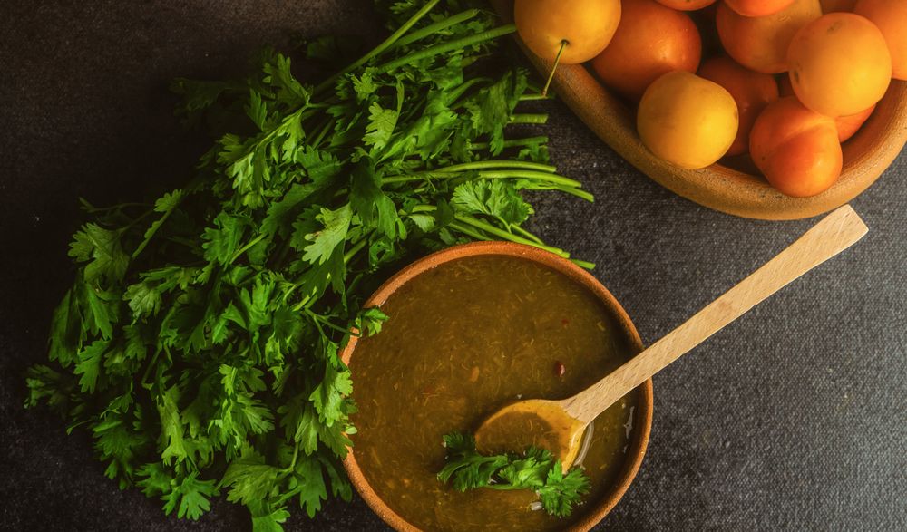 Bowl of plums and fresh parsley with Georgian Tkemali Sauce