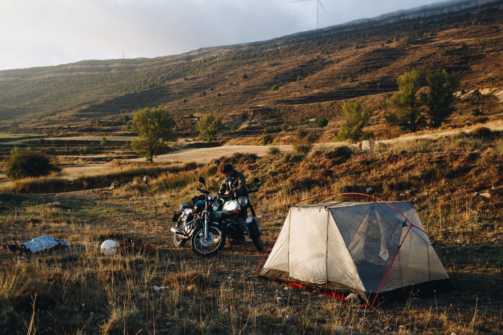 Man with motorcycle and tent, landscape
