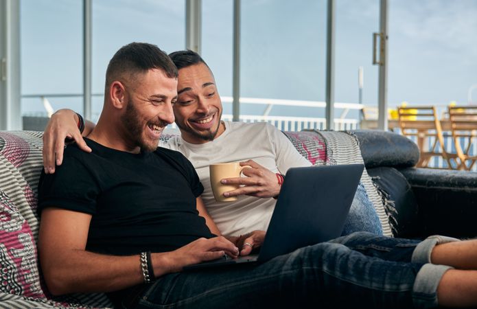 Happy gay couple using laptop at home