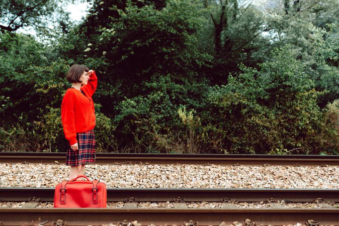 Woman with suitcase walking on railroad ties