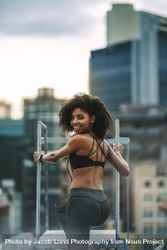 Fitness woman standing on rooftop and looking back 0JdQp4