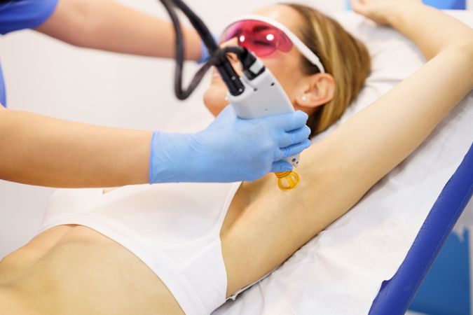 Female receiving underarm laser hair removal at a spa
