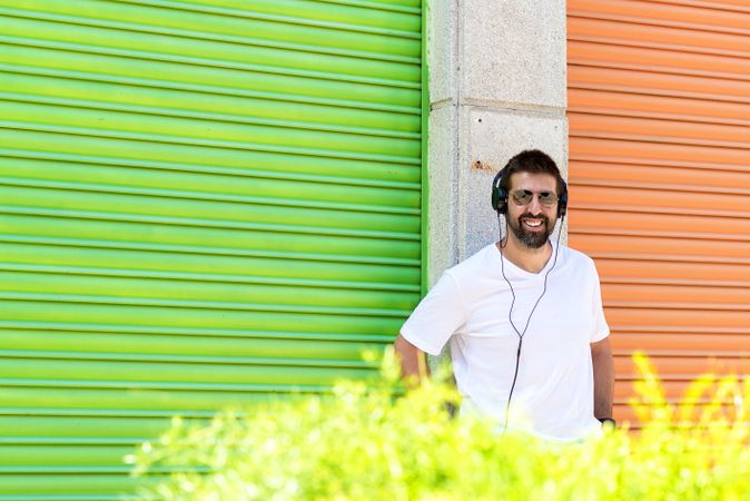 Smiling man leaning on wall between colorful shutters