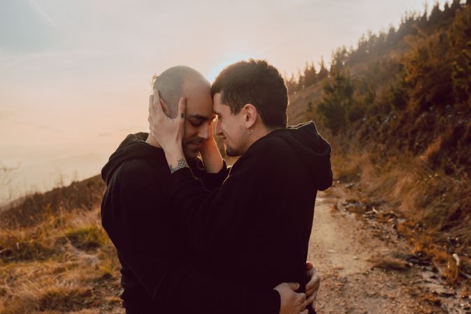 Men hugging and kissing in forest
