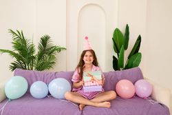 Young girl celebrating birthday at home with gifts and balloons.