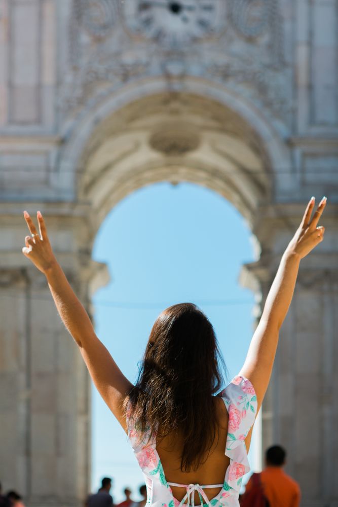 Happy woman showing peace signs while standing against picturesque arch