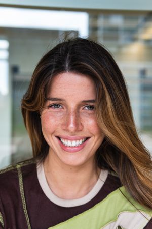 Attractive happy woman standing near modern building wall on street
